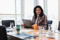 Портрет уверенной деловой женщины с ноутбуком за столом в конференц-зале — стоковое фото