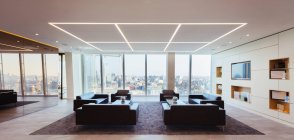 Sofás en el moderno salón de oficinas urbano de gran altura - foto de stock