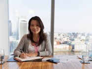 Portrait confident businesswoman planning in highrise conference room — Stock Photo