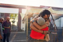 Amici felici che si abbracciano nel parcheggio soleggiato — Foto stock