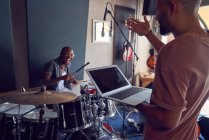 Щасливі музиканти з барабанами та ноутбуком у студії звукозапису — стокове фото
