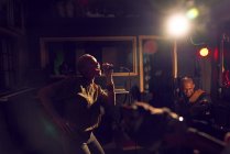 Musicienne chantant dans un micro dans un studio d'enregistrement sombre — Photo de stock
