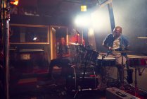 Мужчина играет на гитаре и барабанах в студии звукозаписи — стоковое фото
