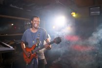 Musicien masculin souriant jouant de la guitare électrique en studio d'enregistrement — Photo de stock