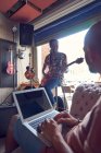 Мбаппе с ноутбуком и электрогитарой в гаражной студии звукозаписи — стоковое фото