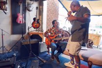 Щасливі музиканти-чоловіки практикують студію запису гаражів — стокове фото