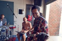 Musiciens masculins souriants pratiquant dans un studio d'enregistrement de garage — Photo de stock