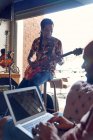 Чоловіки-музиканти з ноутбуком і гітарою практикують в студії звукозапису — стокове фото