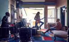 Músicos masculinos que practican en el estudio de grabación de garaje - foto de stock
