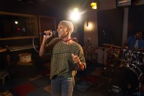 Женщина-музыкант поет в микрофон в студии звукозаписи — стоковое фото