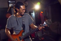 Feliz músico masculino tocando guitarra eléctrica en estudio de grabación - foto de stock