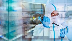 Female scientist in clean suit researching coronavirus in laboratory — Stock Photo