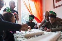 Щаслива сім'я прикрашає різдвяне печиво за столом — стокове фото