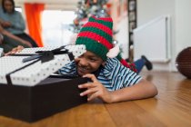 Возбужденный мальчик открывает рождественский подарок на полу в гостиной — стоковое фото