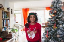 Menina festiva retrato em camisola de Natal e chapéu por árvore — Fotografia de Stock