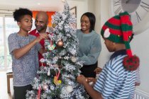 Feliz familia decorando el árbol de Navidad - foto de stock