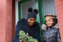 Happy mother and daughter with Christmas wreath on front stoop — Stock Photo