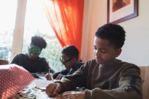 Мальчик пишет рождественские открытки за столом — стоковое фото