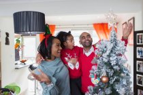 Happy family decorating Christmas tree in living room — Stock Photo