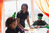 Щаслива мама з дітьми прикрашають різдвяне печиво за столом. — стокове фото