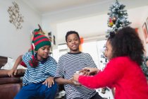 Brothers and sister opening Christmas gifts in living room — Stock Photo