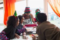 Glückliche Familie schmückt Weihnachtsplätzchen am Tisch — Stockfoto