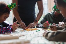 Семья украшает рождественское печенье за столом — стоковое фото
