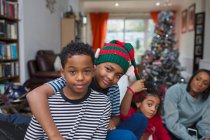 Retrato hermanos felices abrazándose en la sala de estar de Navidad - foto de stock