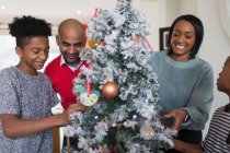 Feliz familia decorando el árbol de Navidad - foto de stock
