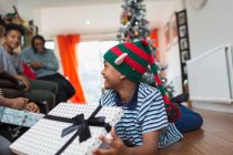 Aufgeregter Junge öffnet Weihnachtsgeschenk auf Wohnzimmerboden — Stockfoto