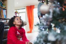 Neugieriges Mädchen blickt zum Weihnachtsbaum auf — Stockfoto