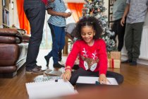 Захоплена дівчина відкриває різдвяний подарунок на підлозі вітальні — стокове фото