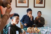 Батько і сини їдять різдвяний торт за столом — стокове фото