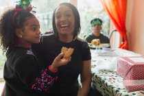 Retrato feliz madre e hija comiendo galletas de Navidad - foto de stock