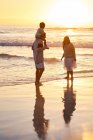 Geschwister laufen bei Sonnenuntergang in der Brandung des Ozeans — Stockfoto