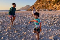 Ritratto felice famiglia giocare a cricket sulla spiaggia soleggiata — Foto stock