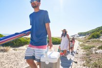 Famiglia che trasporta attrezzature da spiaggia sul lungomare soleggiato — Foto stock