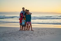 Ritratto felice famiglia sulla spiaggia dell'oceano al tramonto — Foto stock
