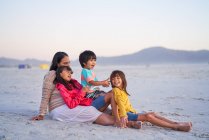 Famille heureuse relaxant sur la plage — Photo de stock