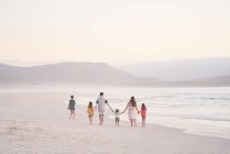 Семья, держащаяся за руки, гуляющая по океанскому пляжу, Кейптаун, Южная Африка — стоковое фото