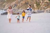 Felice famiglia in esecuzione sulla spiaggia — Foto stock