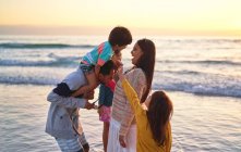 Glückliche Familie watet in der Brandung des Ozeans am Strand von Sonnenuntergang — Stockfoto