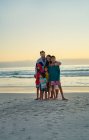 Портрет щасливої любовної сім'ї на березі океану заходу сонця — стокове фото