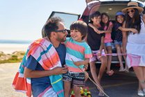 Щаслива сім'я поза машиною на сонячному пляжі парковка — стокове фото