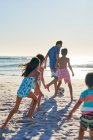 Familie spielt Fußball am sonnigen Strand am Meer — Stockfoto