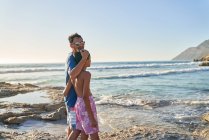 Ritratto felice padre e figlio passeggiando sulla spiaggia soleggiata dell'oceano — Foto stock