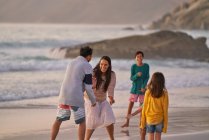 Famille heureuse jouant sur la plage de l'océan — Photo de stock