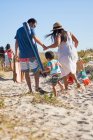 Passeggiate in famiglia nella sabbia sulla spiaggia soleggiata — Foto stock