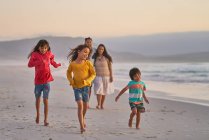 Familia feliz corriendo en la playa del océano - foto de stock