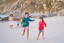 Familia feliz corriendo en la playa - foto de stock